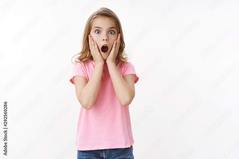 Shocked amazed cute little kid, blond teenage girl, gasping amazed speechless stare camera, touch face from shock, look scared, drop jaw wondered, standing ambushed white background Shocked amazed cute little kid, blond teenage girl, gasping amazed speechless stare camera, touch face from shock, look scared, drop jaw wondered, standing ambushed white background