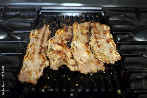 Korean style BBQ shortribs, known as Kalbi, on a cast iron grill in a home kitchen.