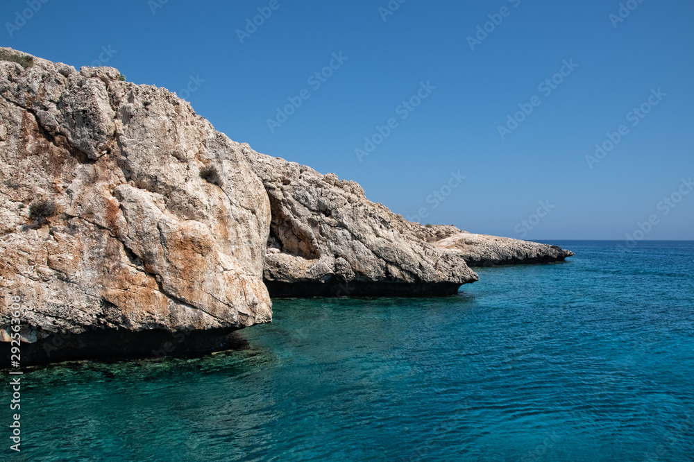 rocky coastline in turquoise sea under blue sky