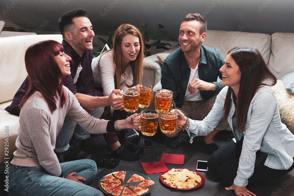 Happy group of friends drinking beer and eating pizza