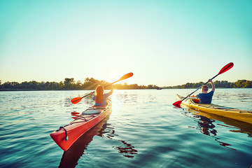People kayak during sunset in the background. Have fun in your free time.