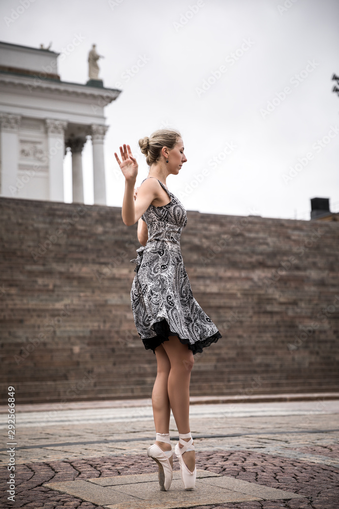 Ballerina is posing in the streets, dancing in pointe shoes