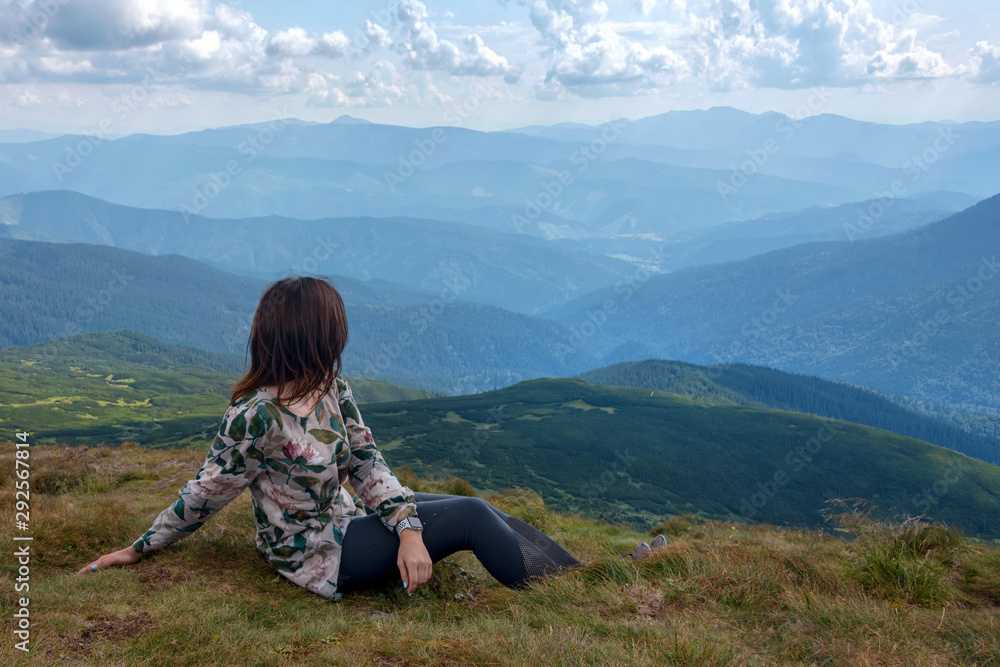 Women sitting at the top of the mountain looking at the valley and mountains. Resting on the highest hill. Wanderlust theme. Carpathian mountains, view from the mountain Hoverla, Ukraine