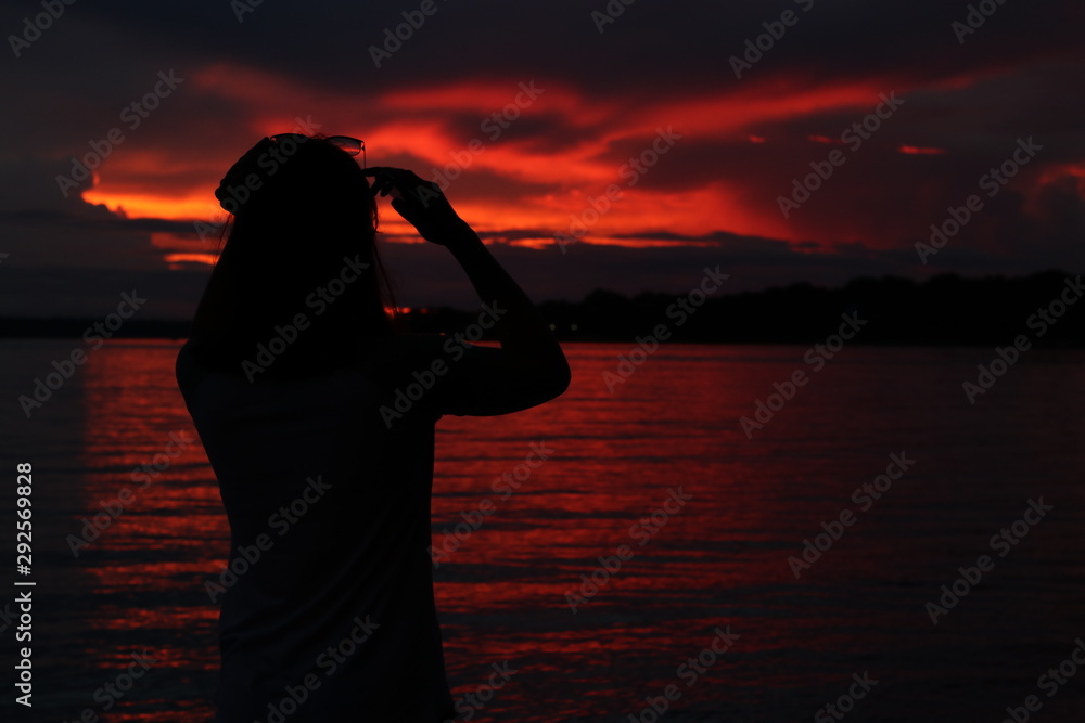 Fototapeta premium silhouette of woman with perfume bottle of water at sunset