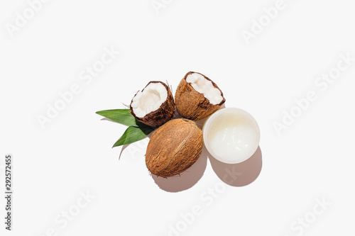 Natural coconuts next to jar of oil