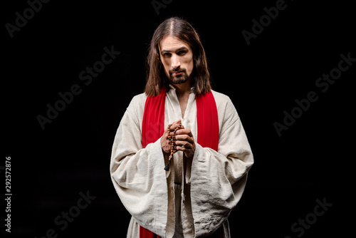 religious man holding rosary beads isolated on black