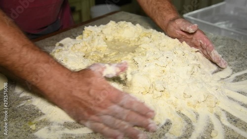 A man prepares to knead the dough for panzerotti or pies: a man kneads dough: in the video, male hands collect flour to make a lump of dough. Durum wheat flour, Senatore Cappelli photo