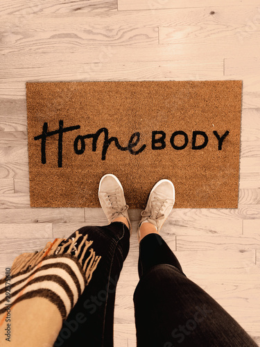 Door mat with Homebody written on it with shoes floor photo