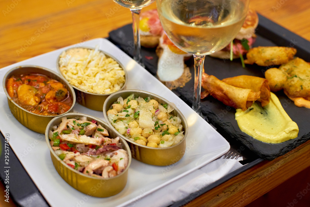 A set of traditional portuguese snacks with codfish, mussels, octopus with a glass of vinho verde