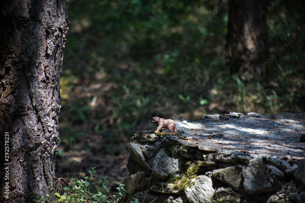 Brown bear walking in forest. Mini bear figure (or toy bear) at the park. Brown bear walking in forest. Mini bear figure (or toy bear) at the park.