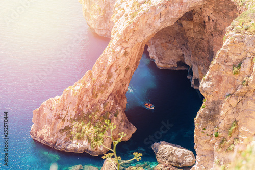 Blue Grotto in Malta. Pleasure boat with tourists runs. Natural arch window in rock