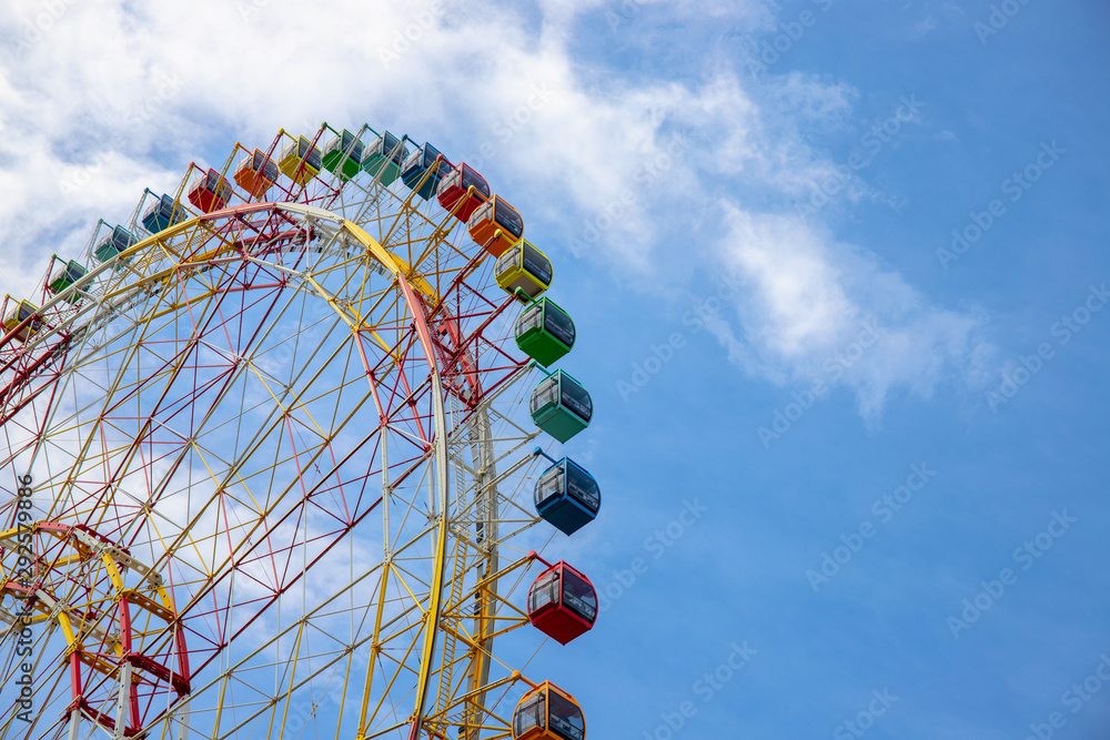 Ferris wheel on blue sky background. Ferris wheel attraction in summer park. Orange metallic construction of attraction.