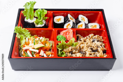 rice with mushrooms. Fresh food portion in japanese bento box with salad, main course. Sushi roll with vegetables. Vegetarian dish.