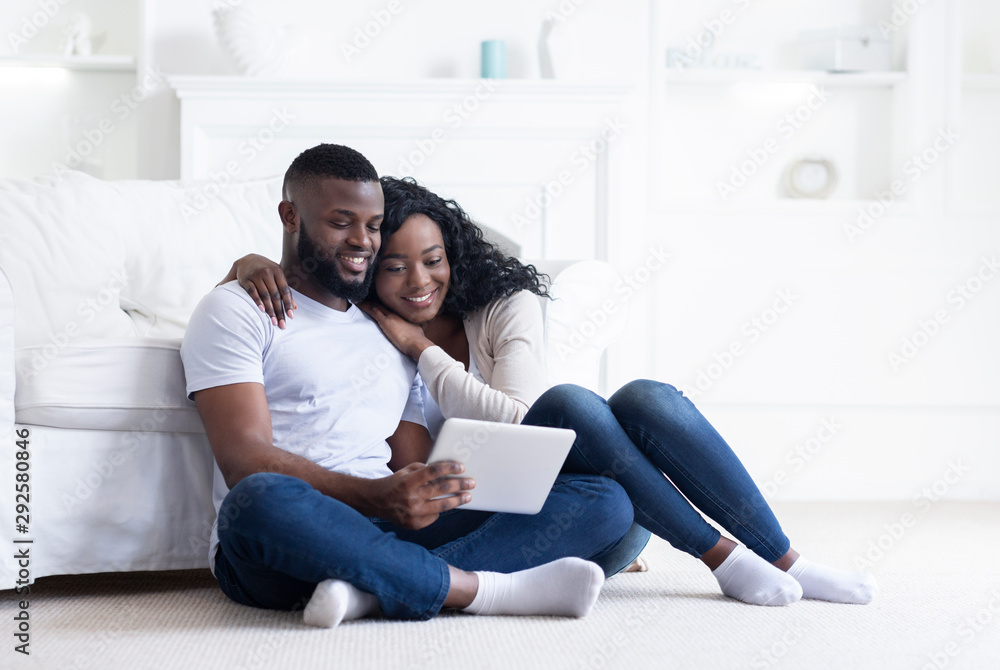 African couple using digital tablet together while sitting at home African couple using digital tablet together while sitting at home