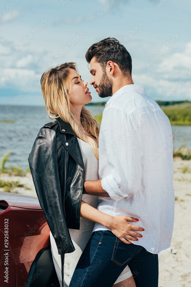 attractive woman and handsome man hugging and kissing outside