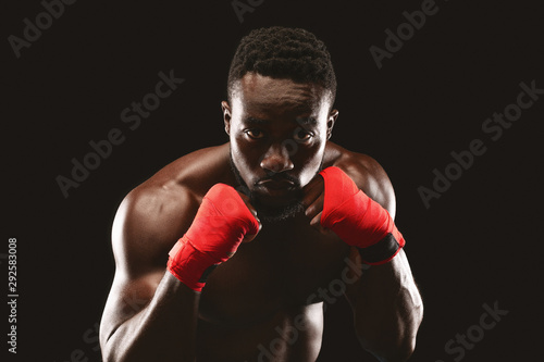 Professional fighter in boxing stance posing over black studio background © Prostock-studio
