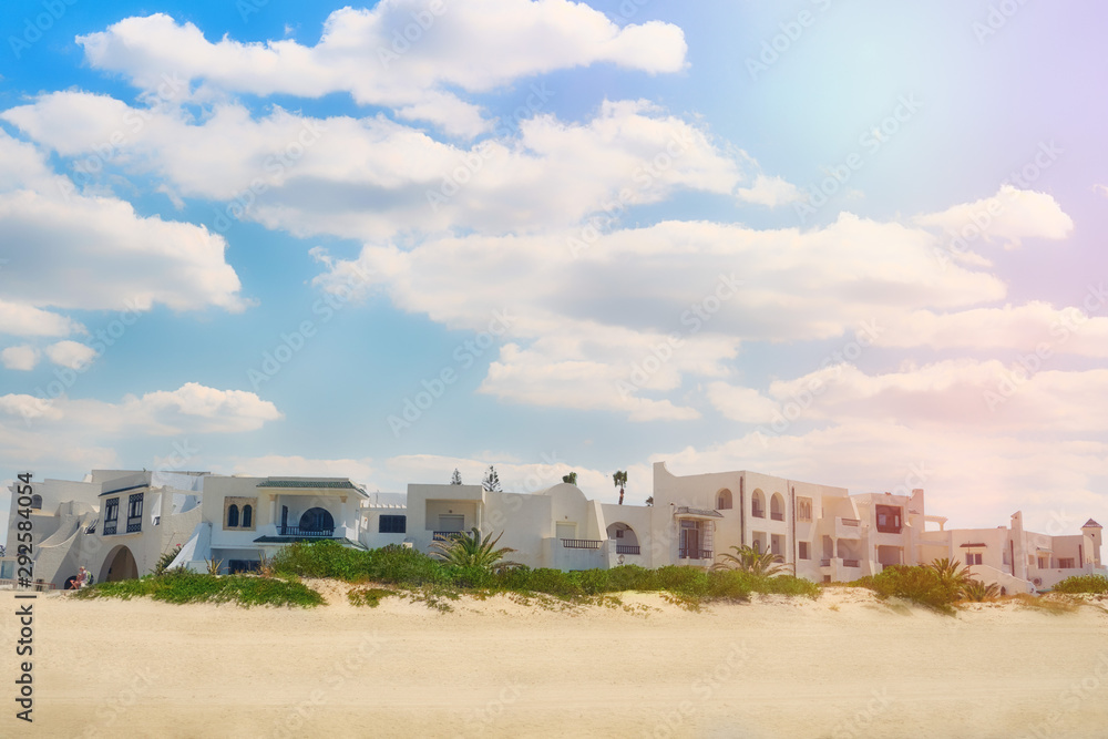 Arabic hotel buildings on a sunny beach. Sun, clouds and tropical scenery, background