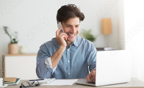 Happy Entrepreneur Talking On Cellphone Sitting At Laptop In Office photo