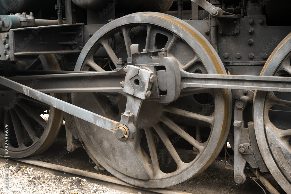 Industrial or transportation or steam punk vintage background with detail of old rusty steam locomotive featuring crank mechanism, frame and  wheels. 