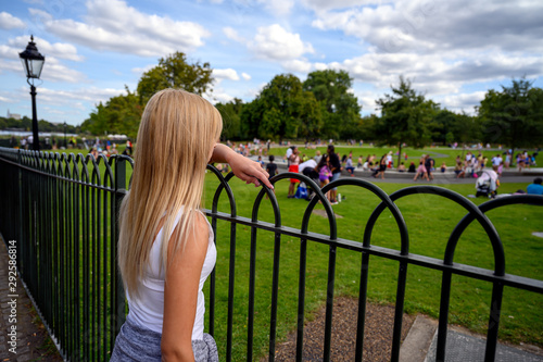 Female tourist watching people playing in the water in the Diana Memorial Fountain, Hyde Park, London, England photo