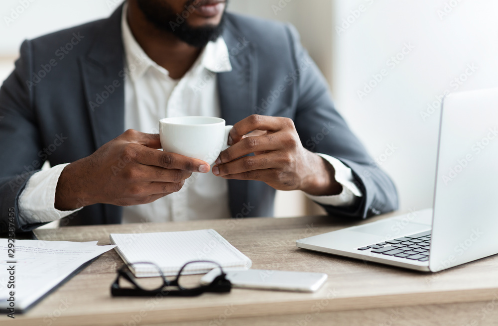African american employee having coffee at workplace in office