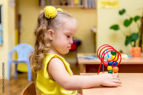 Girl with down syndrom developing motor skills in rehab center for special children photo