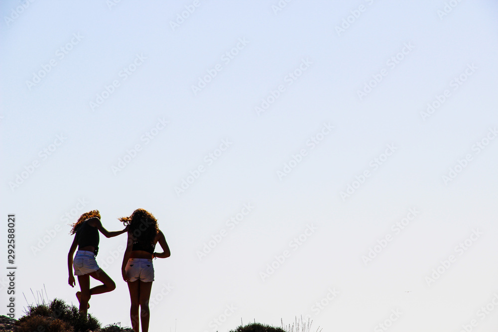 Two girl at the edge of the rocky beach and blue horizon Two girl at the edge of the rocky beach and blue horizon