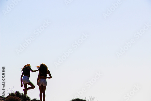 Two girl at the edge of the rocky beach and blue horizon 