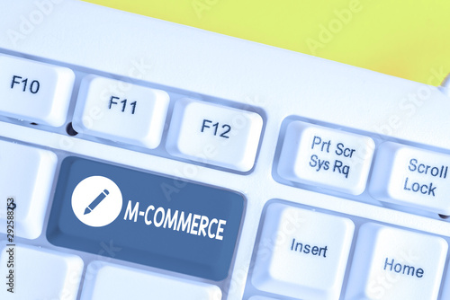 Writing note showing M Commerce. Business concept for commercial transactions conducted electronically by mobile phone White pc keyboard with note paper above the white background photo