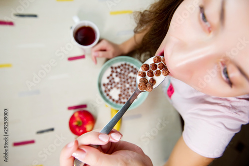 girl is going to eat a spoonful of chocolate cereal with milk and holds a spoon in front of her