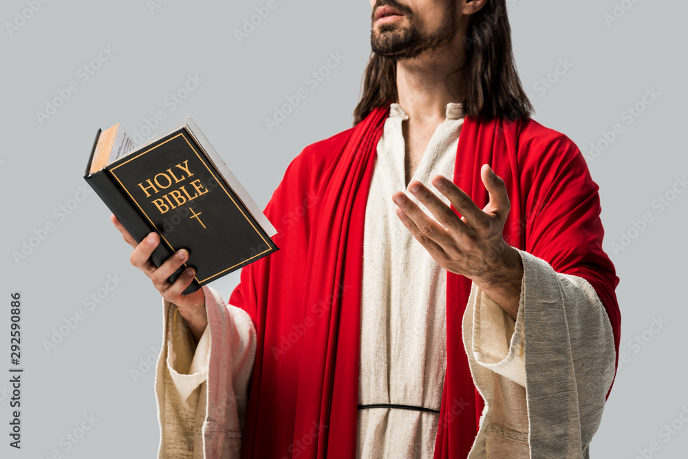 cropped view of religious man in jesus robe holding holy bible and  gesturing isolated on grey Photos | Adobe Stock