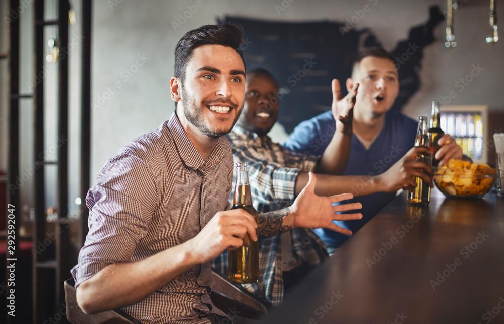 Football fans watching match in sport bar, drinking beer