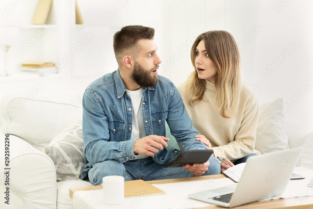 Calculate famiy budget. Shocked couple making financial revision Calculate famiy budget. Shocked couple making financial revision