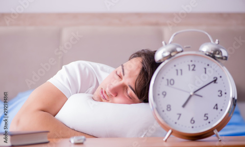 Man in bed frustrated suffering from insomnia with an alarm cloc photo