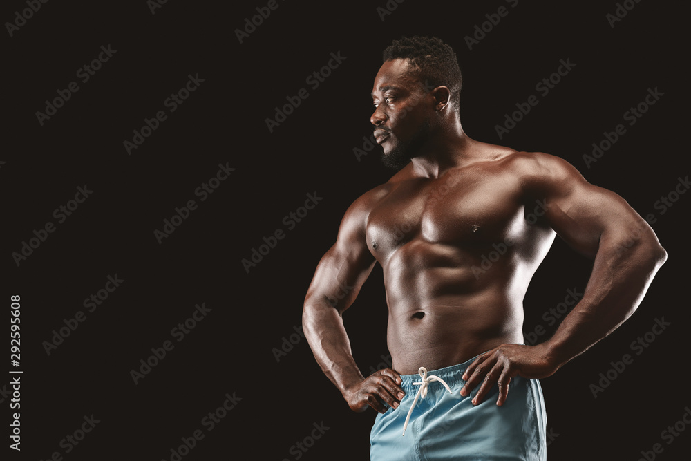 Sexy muscular fitness model showing his body over black background