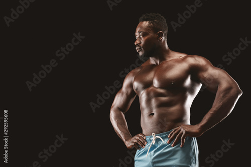 Sexy muscular fitness model showing his body over black background