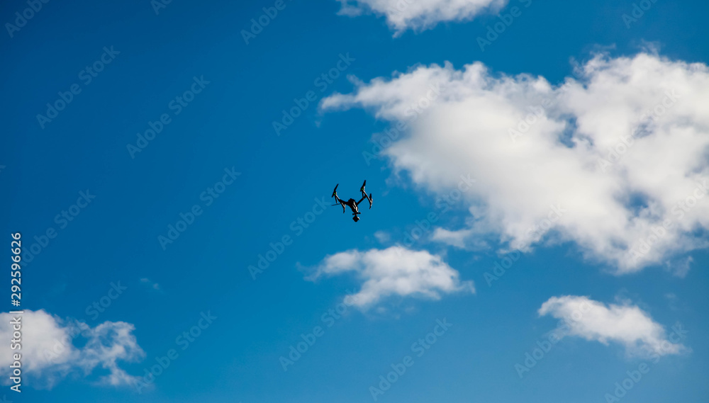 the quadcopter hovered above the clouds against the blue sky the quadcopter hovered above the clouds against the blue sky