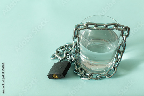 a glass of water wrapped in a chain and closed with a padlock. The concept of the problem of small drinking water resources in the world. Place for text © Rochu_2008