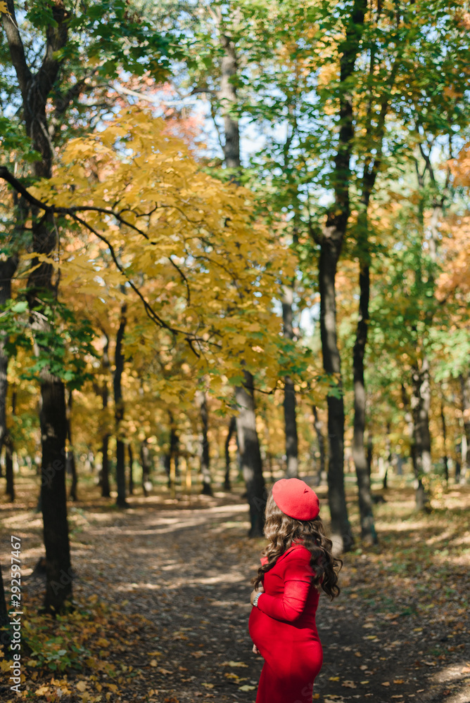 Pregnant girl in a red dress on an autumn background