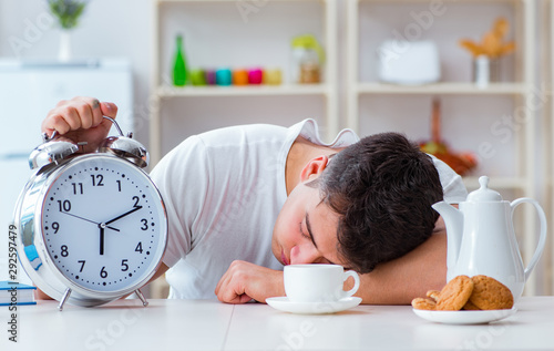 Man with alarm clock falling asleep at breakfast photo