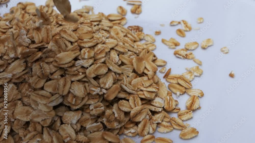 closeup falling oat flakes over white background. Macro Oat flakes rotating. Dry oat flakes grains background. Food background Slow motion . Gastronomy concept, organic healthy food. closeup falling oat flakes over white background. Macro Oat flakes rotating. Dry oat flakes grains background. Food background Slow motion . Gastronomy concept, organic healthy food.