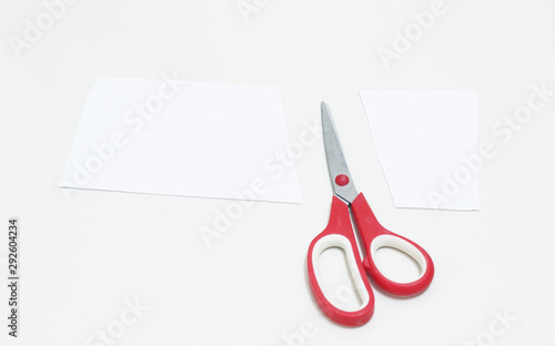 red scissors cutting white paper on white background