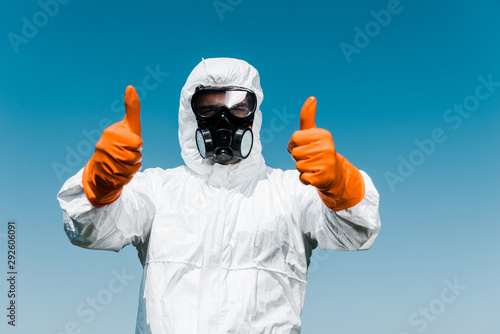 exterminator in protective mask and uniform standing and showing thumbs up photo