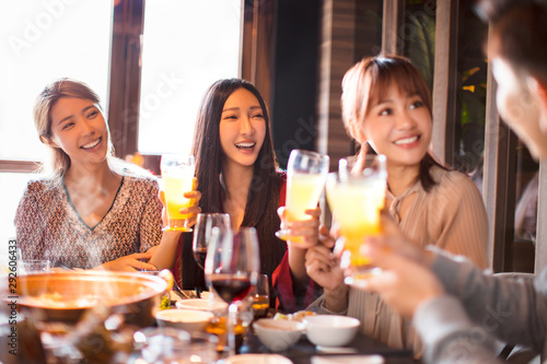 happy young friends eating hot pot in restaurant