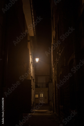 Dark street, an impasse in a dead end back street, with a dim orange light, surrounded by residential buildings in a typical old city center of France