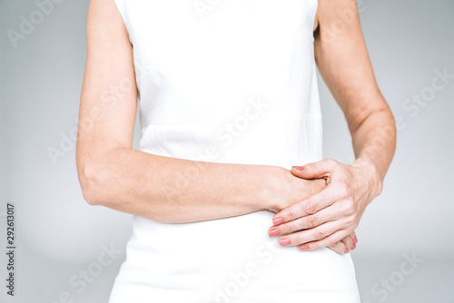 cropped view of mature woman in white dress with crossed hands isolated on grey