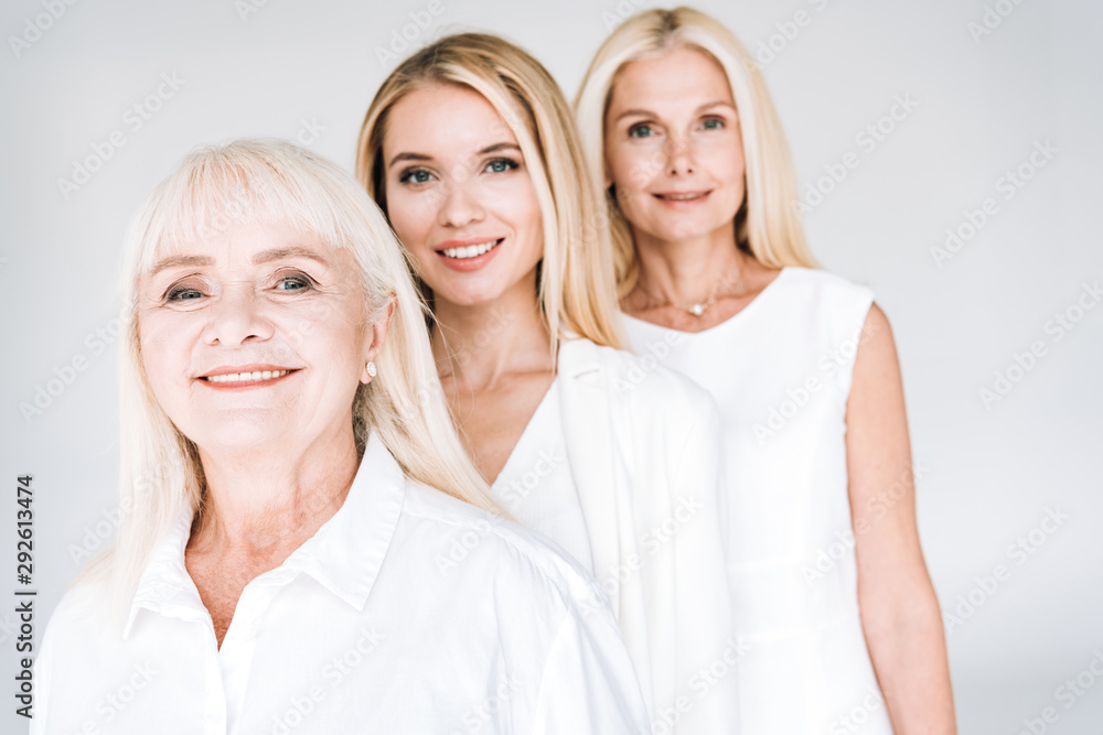 selective focus of attractive three generation blonde women isolated on grey selective focus of attractive three generation blonde women isolated on grey