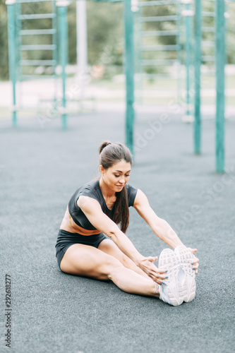 Stretching and warming up before training. Beautiful athletic girl on the Playground.