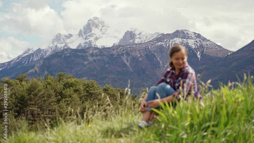 Beautiful view of Alps mountains and blurred image of tourist woman sitting on a green meadow. Travel in Alps mountains Beautiful view of Alps mountains and blurred image of tourist woman sitting on a green meadow. Travel in Alps mountains