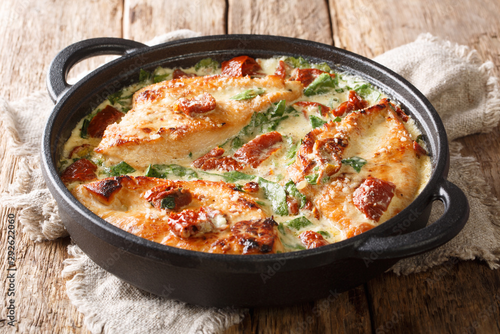 Main dish baked chicken with sun-dried tomatoes and spinach in cheese sauce close-up in a pan. horizontal Main dish baked chicken with sun-dried tomatoes and spinach in cheese sauce close-up in a pan. horizontal